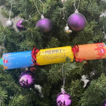 Christmas cracker on christmas tree decorated with purple baubles