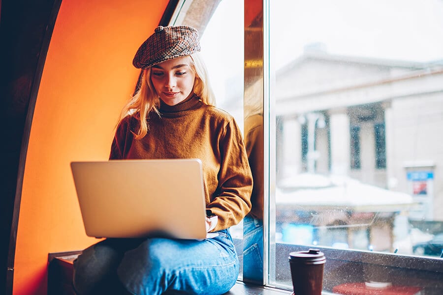 girl with a coffee working in front of her laptop