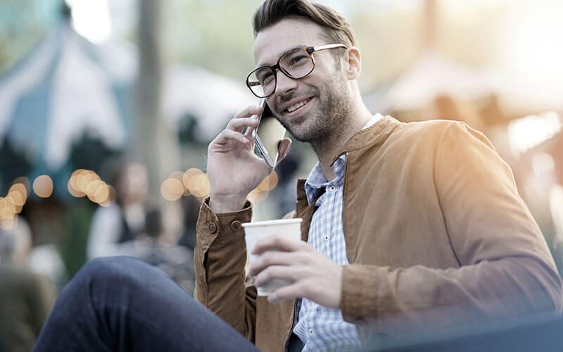 man outside on phone drinking coffee